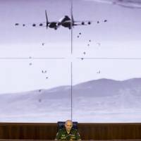 Lt.-Gen. Sergei Rudskoi of the Russian Military General Staff speaks to the media as a video released by the Russian Defense Ministry shows a Russian warplane unload its weapons over target on screen at a Russian Defense Ministry building in Moscow Wednesday. Rudskoi said that fighting in Aleppo will cease for three hours daily to allow humanitarian aid deliveries. | AP