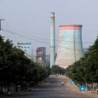A man drives in front of a power plant next to a coal mine on the outskirts of Xiaoyi in China\'s Shanxi province, on Aug. 2. | REUTERS