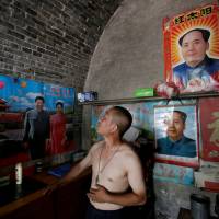 Wang Junqi looks at a crack on a wall inside his damaged house in an area where land is sinking next to a coal mine, in the village of Helin in China\'s Shanxi province on Aug. 2. | REUTERS