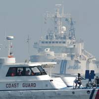 Philippine Coast Guard personnel act as mock pirates while a Japan Coast Guard ship steams toward their boat during a joint coast guard exercise in the waters off Manila Bay on July 13, a day after a U.N.-backed tribunal declared China has no \"historic rights\" to the South China Sea. | AFP-JIJI