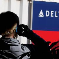 A passenger talks on her phone at a Delta Airlines gate a day before the annual Thanksgiving Day holiday at the airport in Salt Lake City, Utah, on Nov. 21, 2012. | REUTERS