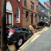 Workers gather Sunday by the sidewalk of Main Street, which caved in after Saturday night\'s flooding in Ellicott City, Maryland. | KEVIN RECTOR / THE BALTIMORE SUN VIA AP