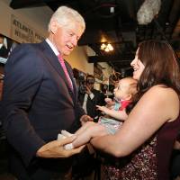 Former President Bill Clinton says hello to Megan Bartlett of Decatur, Georgia, and her 3-month-old daughter, Hannah Rice, as he works the crowd at historic Manuel\'s Tavern Wednesday during a stop in Atlanta. | CURTIS COMPTON / ATLANTA JOURNAL-CONSTITUTION VIA AP