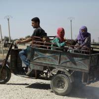 Syrian Kurds flee reported shelling in Hassakeh on Thursday. | AFP-JIJI