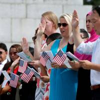 People are sworn in at a naturalization ceremony for new U.S. citizens at the WWII Memorial in Washington on Thursday. | REUTERS