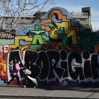 A woman pushes a baby past a graffiti wall with the words “The Aboriginal” in reference to Australia’s indigenous people on Wednesday. Aborigines fight planned nuke waste dump on land they call sacred, fearing 'cultural genocide'