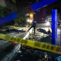Philippine investigators work at the scene where two suspects were shot dead following a shootout with police at a checkpoint along a highway in Manila on Sunday. | AFP-JIJI