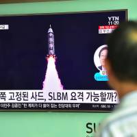 A man watches a TV report about North Korea\'s latest submarine-launched ballistic missile test on a screen set up at a railway station in Seoul last Thursday. | AFP-JIJI
