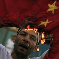 A protester burns the national flag of China during an anti-Syrian regime protest in front of the Arab League headquarters in Cairo in October 2011. | AP