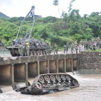A CM11 armoured vehicle lies upside down in a river, killing four of the five soldiers inside, in southern Pingtung, Taiwan, Tuesday. The soldiers were killed when the tank slipped and plunged into the river during heavy rains following an annual firing drill in southern Taiwan. | AFP-JIJI