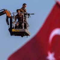 Turkish special forces police officers stand guard as people wave national flags on Sunday during a rally in Istanbul against the July 15 failed military coup. | AFP-JIJI