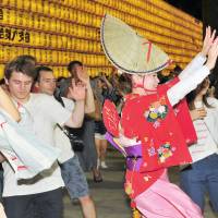 Tourists from home and abroad dance with “Bon odori” performers during the Mitama Matsuri festival at Yasukuni Shrine in Tokyo’s Chiyoda Ward on July 16. | YOSHIAKI MIURA