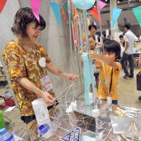 Children gather around Slime Synthesizer, co-created by Dorita Takido (left), at Maker Faire Tokyo 2016 on Sunday. From home-made VR to intentionally lousy robots, hobbyists get their fill at Tokyo expos