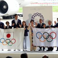 Tokyo Gov. Yuriko Koike (center) poses with the Olympic flag at Haneda airport as the Japanese Olympic delegation returned from Brazil on Wednesday. | SATOKO KAWASAKI