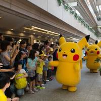 Performers dressed as Pikachu interact with children as they march through a shopping mall during the Pikachu Outbreak event in Yokohama on Aug. 7 last year. 'Pokemon Go' a hit 20 years after franchise debuts