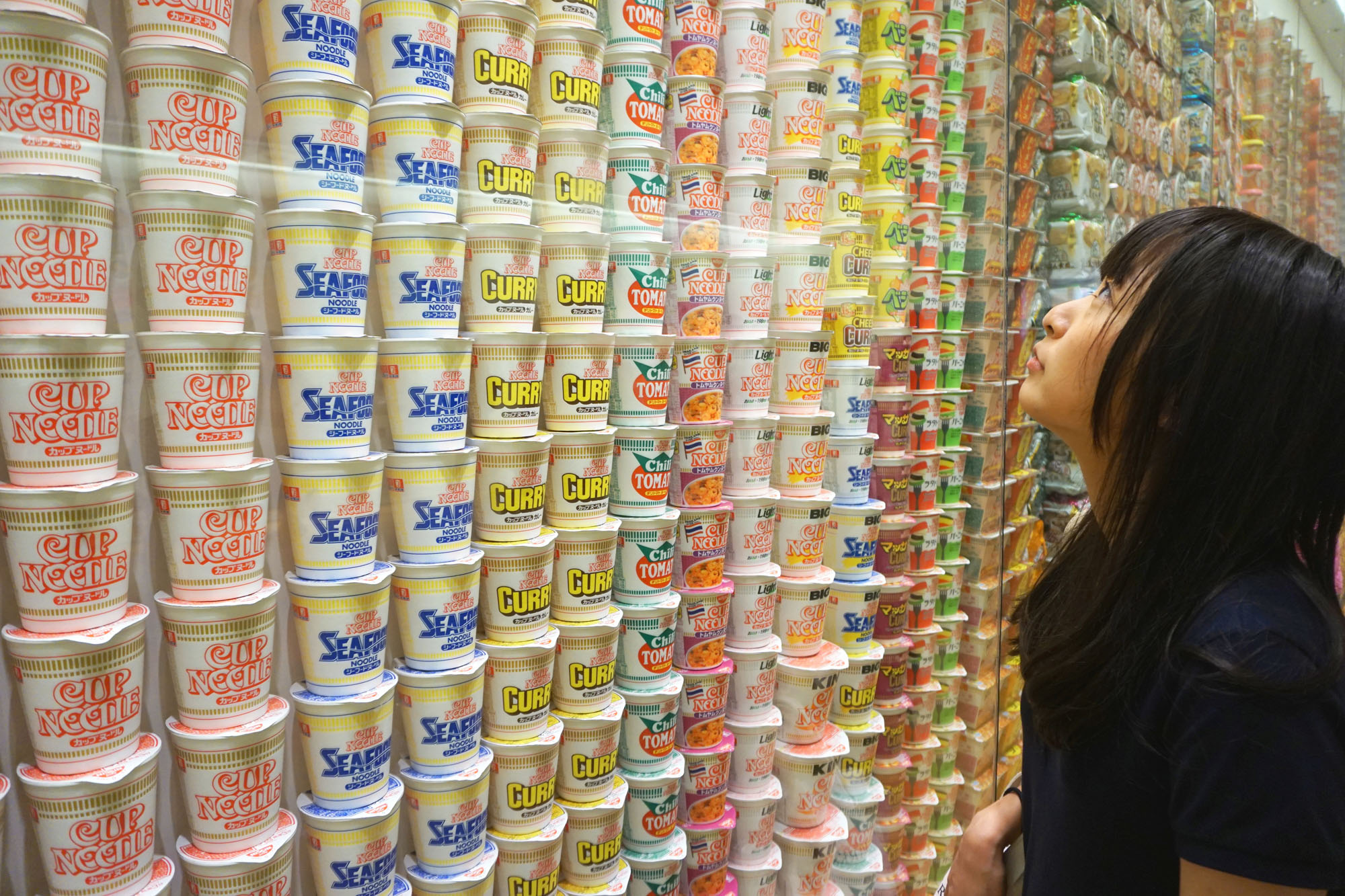 A visitor looks at a wall of instant noodles on display at the Cup Noodles Museum in Yokohama on Aug. 15. | SHUSUKE MURAI