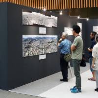 Visitors take in a Japanese photojournalism exhibition at the Tokyo International Forum on Saturday. The display of momentous news events ends on Sept. 9. | KYODO