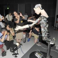 Journalists gather around Alter to take photos of the robot at the National Museum of Emerging Science and Innovation (Miraikan) in Tokyo on July 29. | YOSHIAKI MIURA
