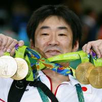 Japan gymnastics coach Takahiro Moriizumi shows off the gold medals after the Japanese team won the men\'s team event on Monday at the 2016 Summer Olympic Games in Rio de Janeiro. | KYODO