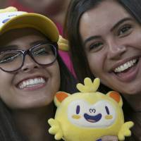 Female fans enjoy a women\'s soccer game between Sweden and China holding an Olympic mascot on Tuesday at Mane Garrincha Stadium. | REUTERS