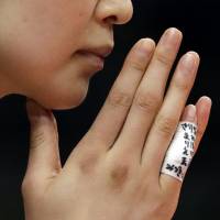 Saori Kimura raises her hand to her face as she awaits the next serve during a women\'s preliminary volleyball match against Argentina on Sunday at the 2016 Summer Olympics in Rio de Janeiro. The names of teammates who did not make the final Olympic roster are written on bandages on her fingers. | AP