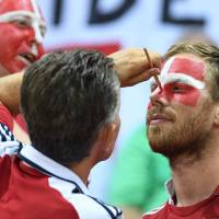A Danish fan paints a flag on the face of another one prior to the men\'s semifinal handball match between Poland and Denmark in the Rio Olympics at the Future Arena on Friday. | AFP-JIJI