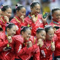 Japan team members pose with their bronze medals following the synchronized swimming team free routine final on Friday. | AP