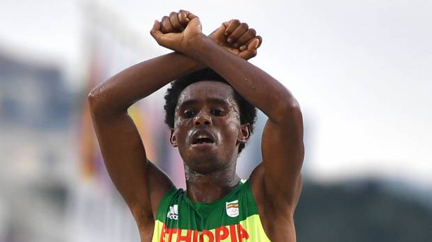 Ethiopia’s Feyisa Lilesa gestures as he finishes the men’s marathon on Sunday in Rio de Janeiro. Lilesa, who was protesting against his homeland’s government, earned the silver medal. Kipchoge captures marathon title; Lilesa makes statement
