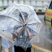 A man\'s umbrella proves to be no match for the heavy winds of Typhoon Mindulle. | SATOKO KAWASAKI