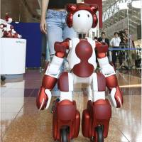 Hitachi Ltd\'s EMIEW3 humanoid robot guides a woman during a demonstration at Tokyo\'s Haneda airport on Friday. | KYODO
