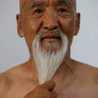 Li Liangui touches his beard as he demonstrates \"suogugong\" kung fu skills for the camera at his apartment in Beijing on July 2. | REUTERS
