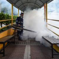 A pest control worker fumigates a school corridor on the eve of the annual national primary school evaluation test in Kuala Lumpur on Sunday. | AFP-JIJI