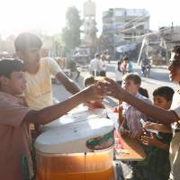 A Syrian boy serves juice on the third day of the Al-Adha Eid (Festival of Sacrifice) Muslim holiday in the rebel-controlled town of Hamouria, in the eastern Ghouta region on the outskirts of the capital Damascus, on the second day of an internally backed cease-fire for Syria came into effect as part of a hard-fought deal to bring an end to the war between rebels and regime fighters on Wednesday. | AFP-JIJI
