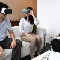 Couples try out goggles developed by mobile phone app developer Ateam Inc. The device lets people see what their wedding might look like. | CHUNICHI SHIMBUN
