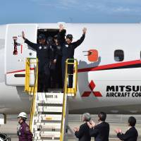 The pilots and crew of a Mitsubishi Regional Jet are welcomed by ground staff after a test flight at Nagoya Airport in Aichi Prefecture last November. | AFP-JIJI