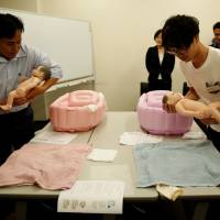 Yuji Inoue (left), 42, and Takashi Tayama (right), 35, take part Sunday in an ikumen, or child-rearing, course for men in Tokyo organized by the Osaka-based company Ikumen University. | REUTERS