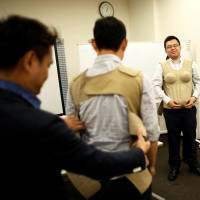 Participants wear 7-kg pregnancy jackets as they take part in an ikumen child-rearing course for men organized by Osaka-based company Ikumen University in Tokyo on Sunday. | REUTERS