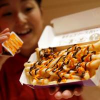 A McDonald\'s staff member poses with the company\'s \"Halloween Choco Fries\" at a McDonald\'s restaurant in Tokyo on Thursday. | REUTERS