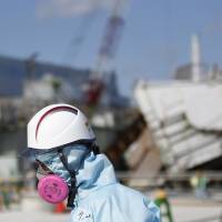 A nuclear worker passes debris at the Fukushima No. 1 plant in February. | VIA BLOOMBERG