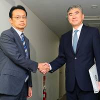 Sung Kim (right), U.S. special representative for North Korea policy, and Kenji Kanasugi, director-general of the Foreign Ministry\'s Asian and Oceanian Affairs Bureau, shake hands before they held talks on coordinating steps against North Korea in Tokyo on Sunday. | POOL / VIA KYODO