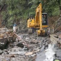 Workers restore a road that was damaged by Typhoon Lionrock on Tuesday in the town of Iwaizumi, Iwate Prefecture. | KYODO