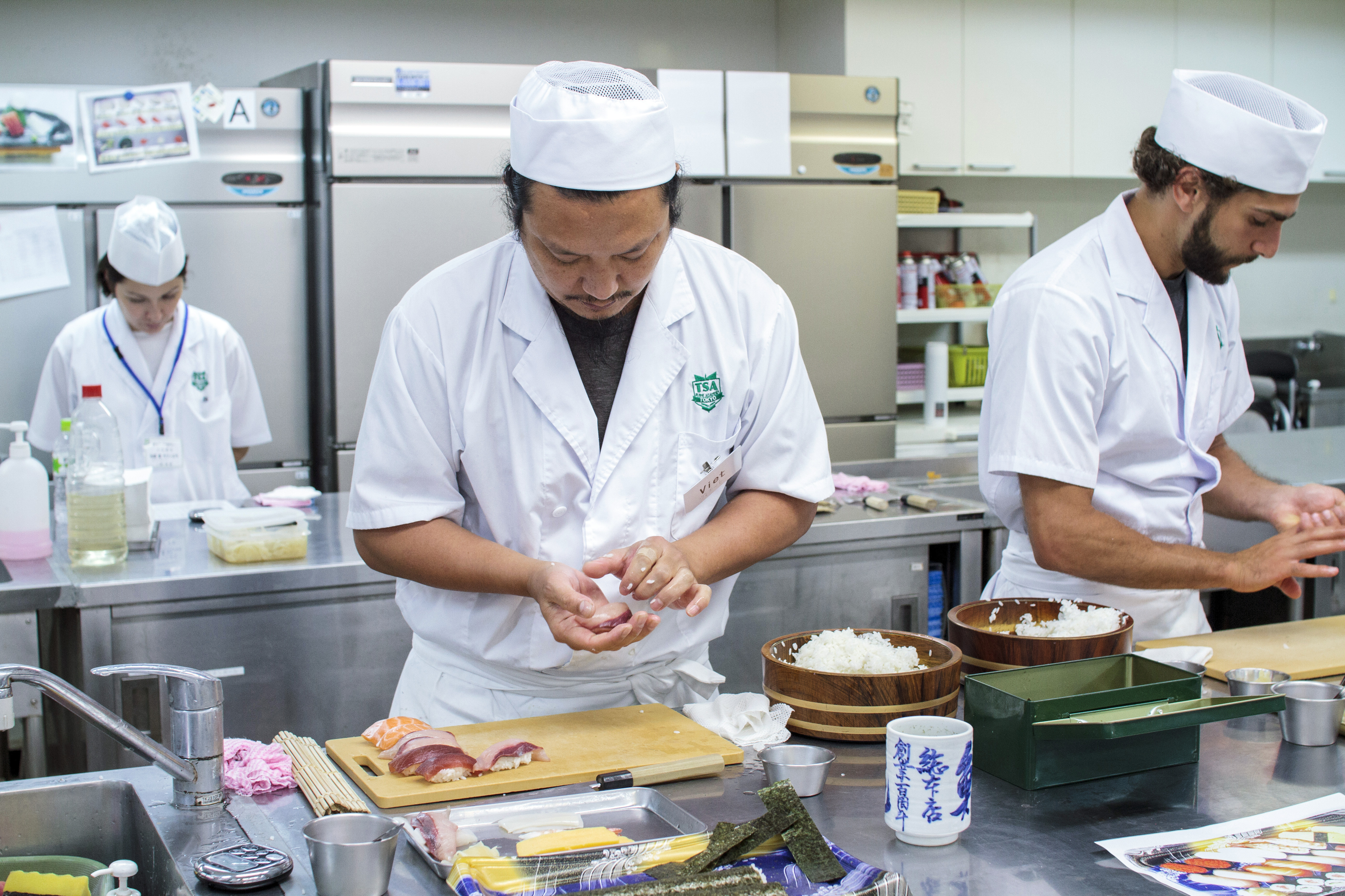 Pressure is on: International students Viet Tran (center) and Anthony Zeidan (right) prepare sushi rolls during a time trial at Tokyo Sushi Academy. | JAMES HADFIELD