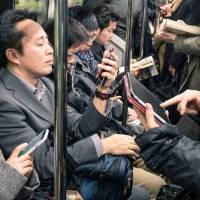 Communication cues: Commuters use smartphones and tablets in an underground train in March 2015. | ISTOCK