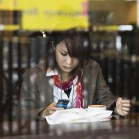 Spoiled for choice: A woman in a cafe sends a text message in Tokyo in May 2010. | ISTOCK