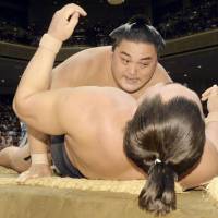Maegashira Okinoumi takes down yokozuna Harumafuji on Tuesday at the Autumn Grand Sumo Tournament. | KYODO