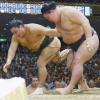 Ozeki Goeido (right) shoves Okinoumi out of the raised ring on Saturday at the Autumn Grand Sumo Touranament. | KYODO