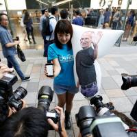 Apple fan Ayano Tominaga poses with her new iPhone 7 and a Steve Jobs cushion in Tokyo\'s Omotesando shopping district on Friday, when the new smartphone went on sale. The Pokemon Go Plus device was released the same day. | REUTERS