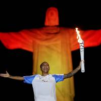 Brazilian judo gold medalist Rafaela Silva holds the Paralympic torch during a ceremony at Rio de Janeiro\'s Christ the Redeemer statue on Tuesday ahead of the 2016 Rio Paralympics, which open on Wednesday night. | REUTERS