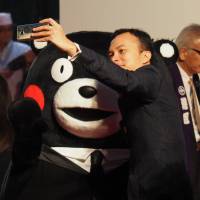 A red carpet participant takes a selfie with Kumamon, who\'s appropriately in formal attire. | MARK THOMPSON