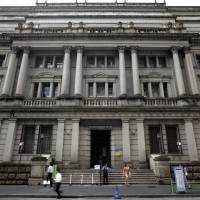 Pedestrians pass the Bank of Japan headquarters in Tokyo. | BLOOMBERG